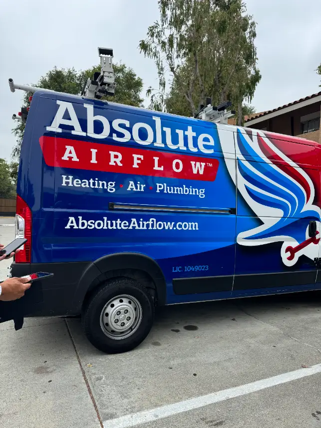 A van labeled "Absolute Airflow" with graphics for heating, air, and plumbing services is parked on a street, ready to respond to your needs. Don't hesitate to contact them for top-notch home solutions.