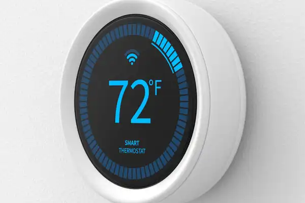 A round smart thermostat, expertly installed, displays 72°F in crisp blue digital numbers alongside a Wi-Fi symbol on a pristine white wall.