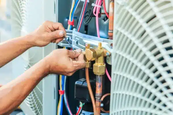 A technician carefully adjusts the wires and valves in an HVAC unit, ensuring optimal air conditioning maintenance.